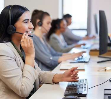 A line of call center agents working with customers, speaking into headsets - coolest call center in Tijuana.