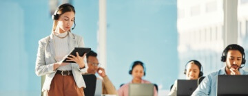 Professional businesswoman leading and supervising a group of Call Center employees, providing guidance and generating reports at office.
