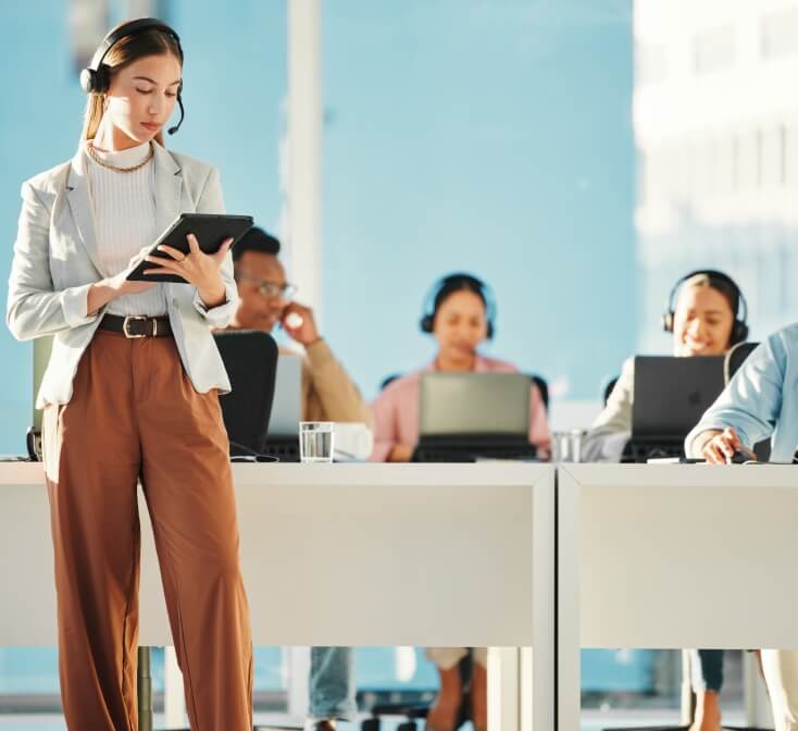 Professional businesswoman leading and supervising a group of Call Center employees, providing guidance and generating reports at office.