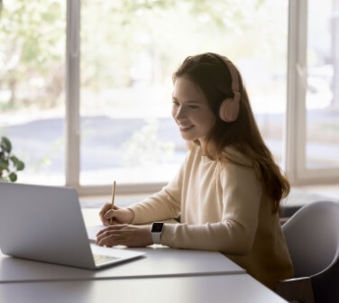Girl wearing headphones using laptop in call center, improve foreign language skills, gain new knowledge online.