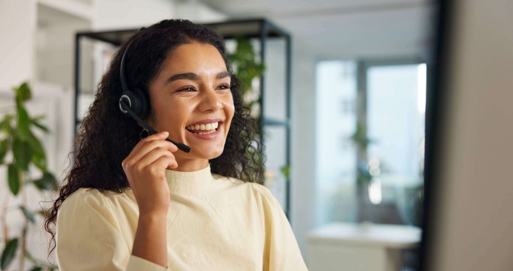 Talking, happy woman and customer service in call center with headset, communication and online consulting and improving her English language skills. Smile, friendly consultant and sales office for CRM contact support, advice or business.