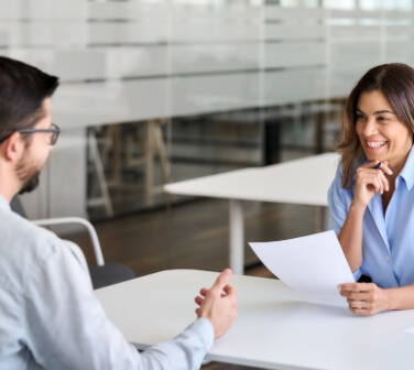 Smiling professional female HR having job interview meeting with male recruit to work in the best call center job in Tijuana.