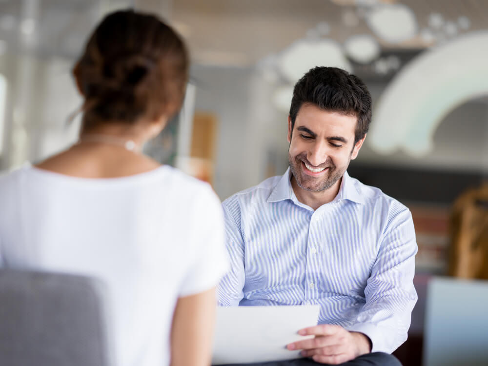 Smiling manager interviews a woman for a job at the best call center in Tijuana.