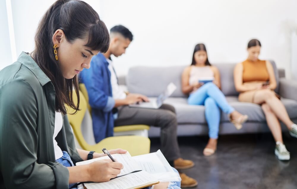 Job, interview and people in office or waiting room in lobby reading recruitment info and notes. Resume, woman or writing cv application in human resource reception or research vacancy opportunity.