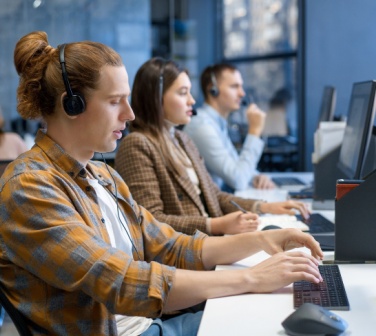 Diverse group of young professionals working and training at a call center.