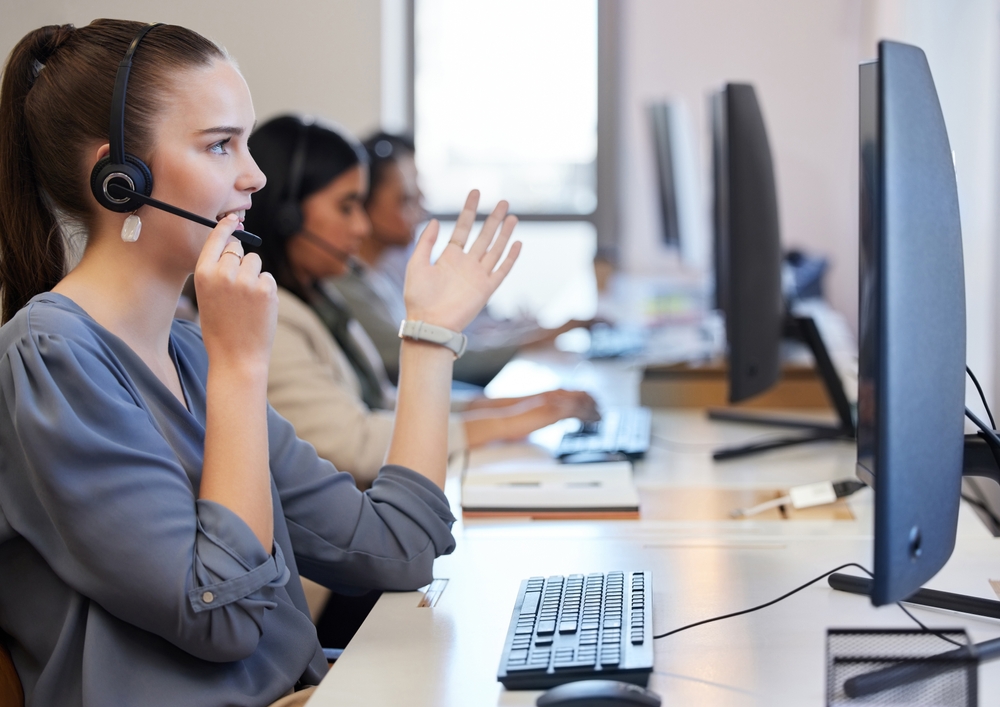 Providing the best solution and direction. Shot of a young call center agent working in an office with her colleagues in the background, training for a professional career.