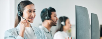 A woman agent with problem-solving skills in call center jobs, smiling as she attends to a customer.