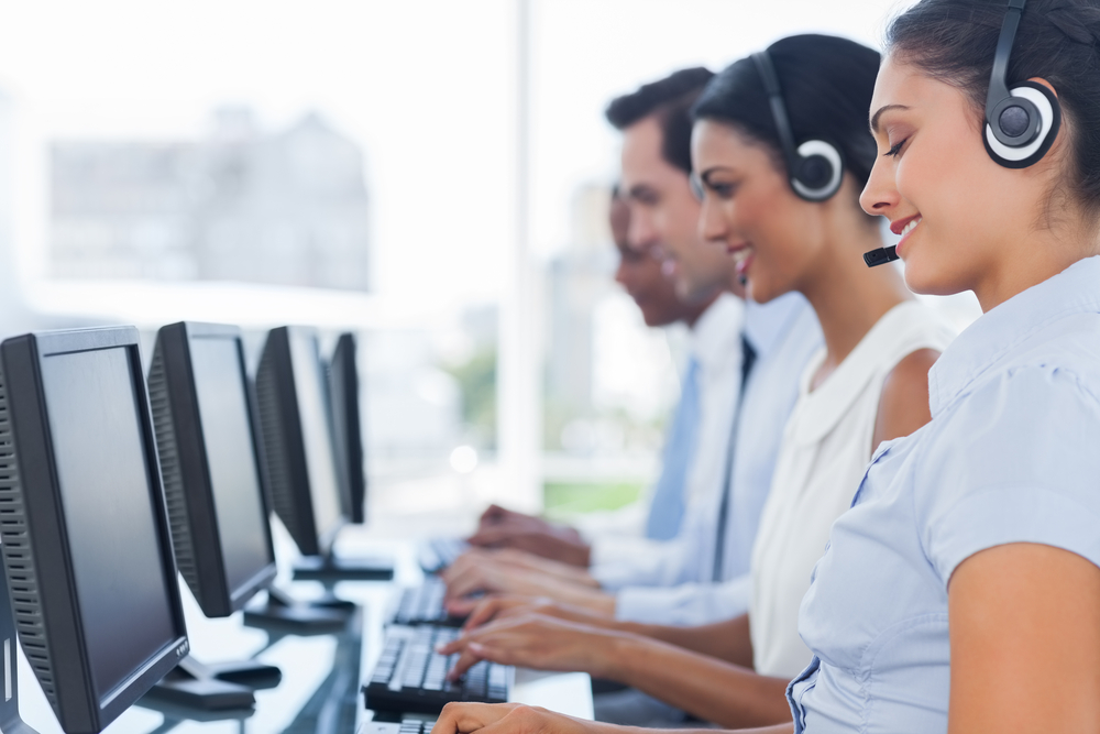Call center team working at their computers, representing financial independence for young professionals.