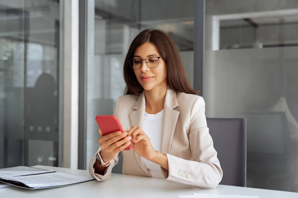A professional checking a smartphone at a modern desk, representing how call center global careers support long-term growth
