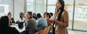 A confident female leader engages a diverse team in a professional workshop, promoting teamwork and fresh ideas in a bright office environment with her call center leadership skills.