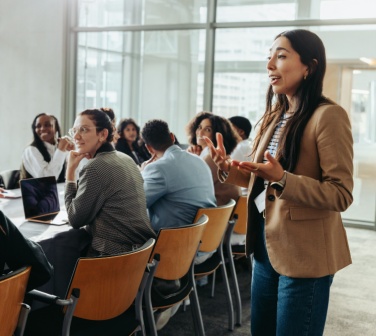 A confident female leader engages a diverse team in a professional workshop, promoting teamwork and fresh ideas in a bright office environment with her call center leadership skills.