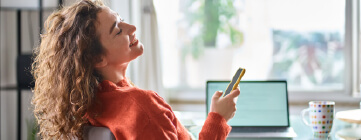 Woman relaxing at home with her phone, practicing work-life boundaries after a stressful shift.