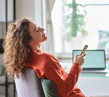 Woman relaxing at home with her phone, practicing work-life boundaries after a stressful shift.