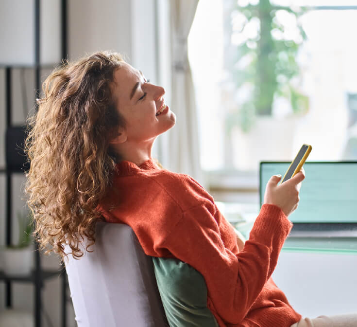 Woman relaxing at home with her phone, practicing work-life boundaries after a stressful shift.