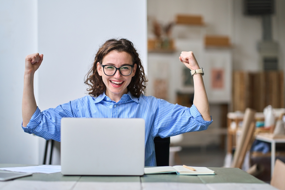 Woman celebrates at her laptop after a job search update, showing the excitement of trying to find work in Mexico.