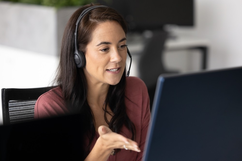 Female call center agent using a detective mindset to understand customer needs while speaking through her headset.