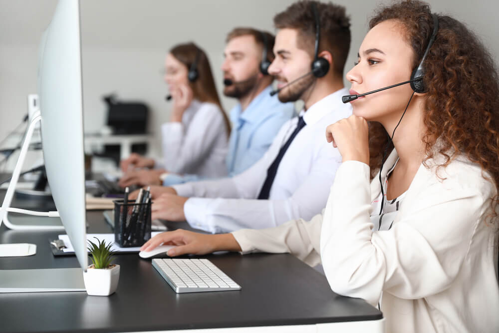 Agentes de call center atienden llamadas frente a sus computadoras, mostrando concentración durante los primeros 30 días en un call center.