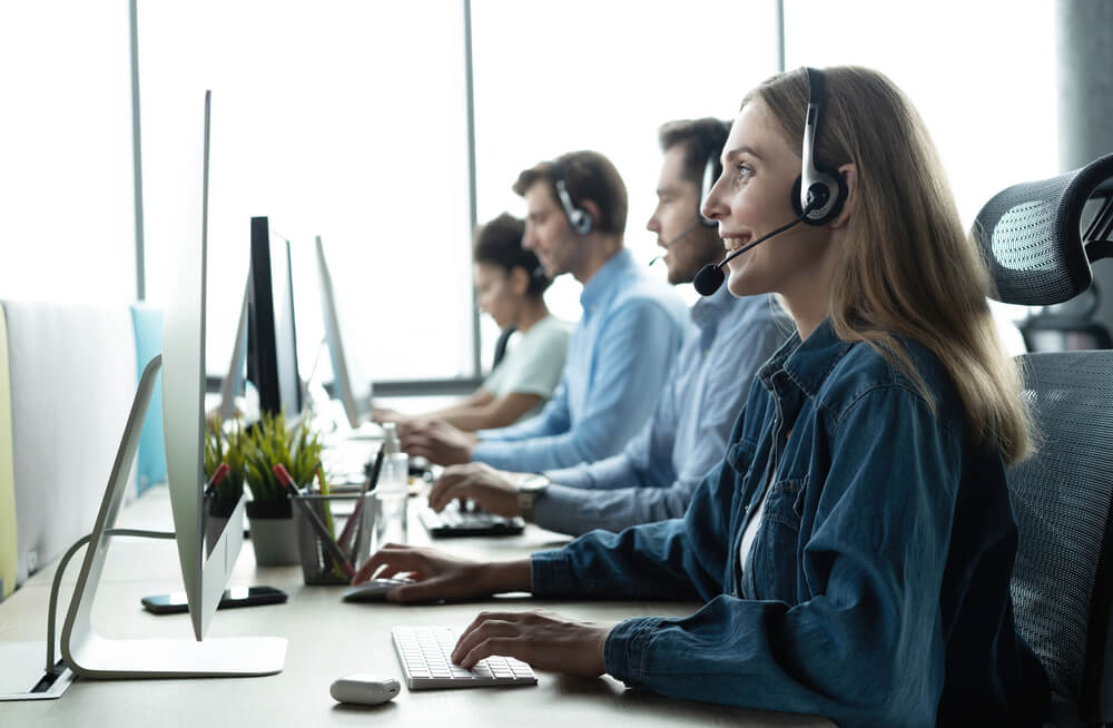 Equipo de agentes trabajando con audífonos frente a sus computadoras, mostrando el aprendizaje y ritmo de los primeros 30 días en un call center.