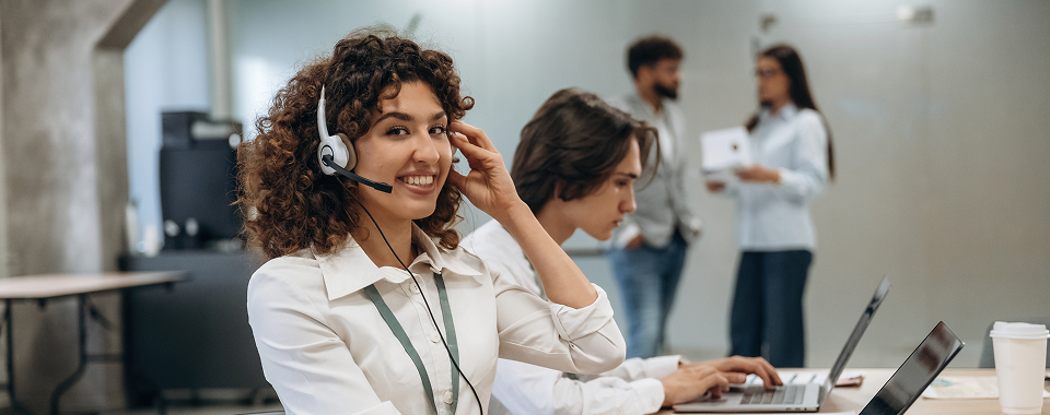 Agente de call center con audífonos trabajando en una computadora y desarrollando habilidades útiles para cualquier profesión.