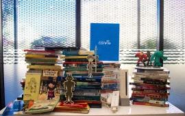 A table full of books and toys, featuring a Confie folder in the background.