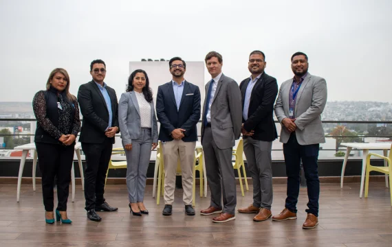 Group of Confie employees posing on a terrace with a city view.