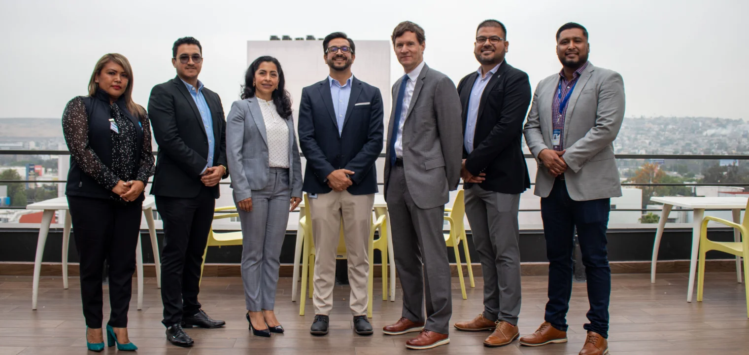 Group of Confie employees posing on a terrace with a city view.