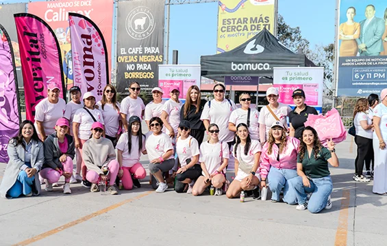 Three Seguros Confie employees and Xolos de Tijuana representative smiling with signs and a recognition award at a community event.