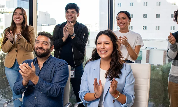 Young people smiling and clapping in a meeting.