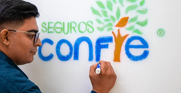 Young man drawing the logo of Seguros Confie.