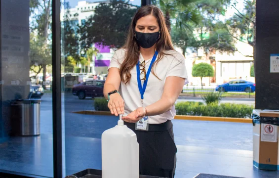Young woman in the lobby of Seguros Confie using hand sanitizer.