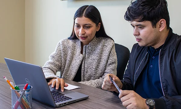 A woman and a man viewing a laptop.