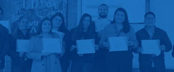 A group of people in an office holding their diplomas.