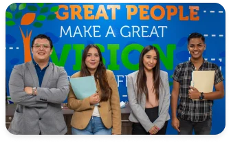 Four young coworkers smiling and standing in an office.