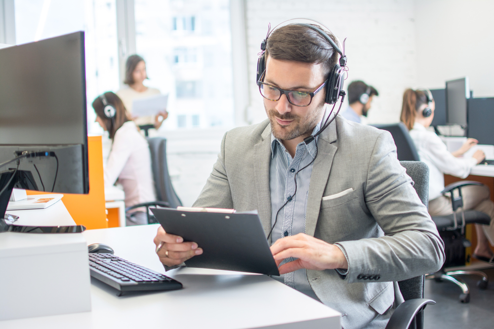 male customer service representative on call with customer holding clipboard