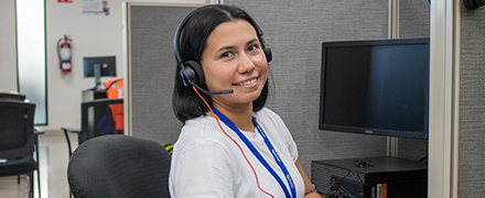 Happy female agent with her headset in front of her computer