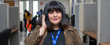 Happy female agent holding her headset in Confie offices with other agents in background
