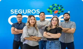 Group of professional insurance agents standing confidently in front of a Seguros CREE banner