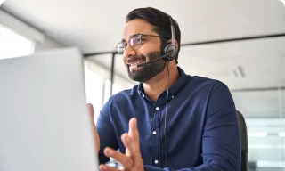 Smiling male support service operator talking to customer sitting at desk young professional business