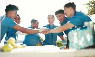 Group of young people playing soccer and celebrating on a sunny field