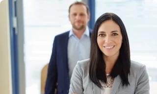 smiling businesswoman with man standing in background