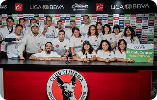 A group of people poses together behind a table in a press room with Club Tijuana and Liga BBVA branding in the background.